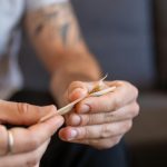 Hombre liando un cigarro con tabaco natural sobre una mesa de madera