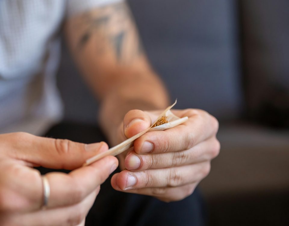 Hombre liando un cigarro con tabaco natural sobre una mesa de madera